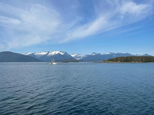 Auke Bay with snow capped mountains in the distance and wisps of clouds in the blue sky